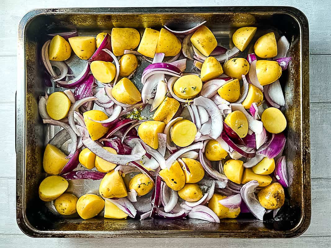 new potatoes with red onion in a roasting dish