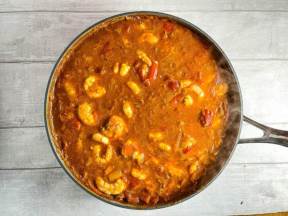 uncooked prawns added to balti curry sauce in pan