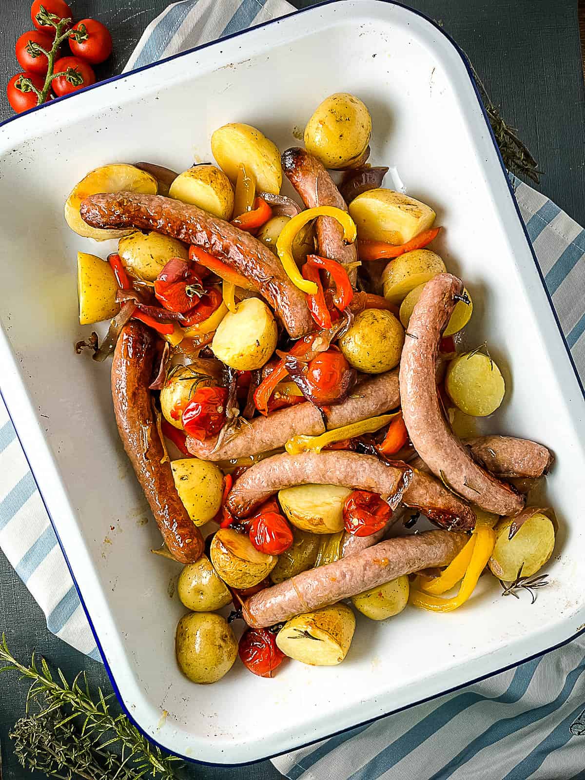 sticky sausage tray bake cooked with potatoes peppers and tomatoes