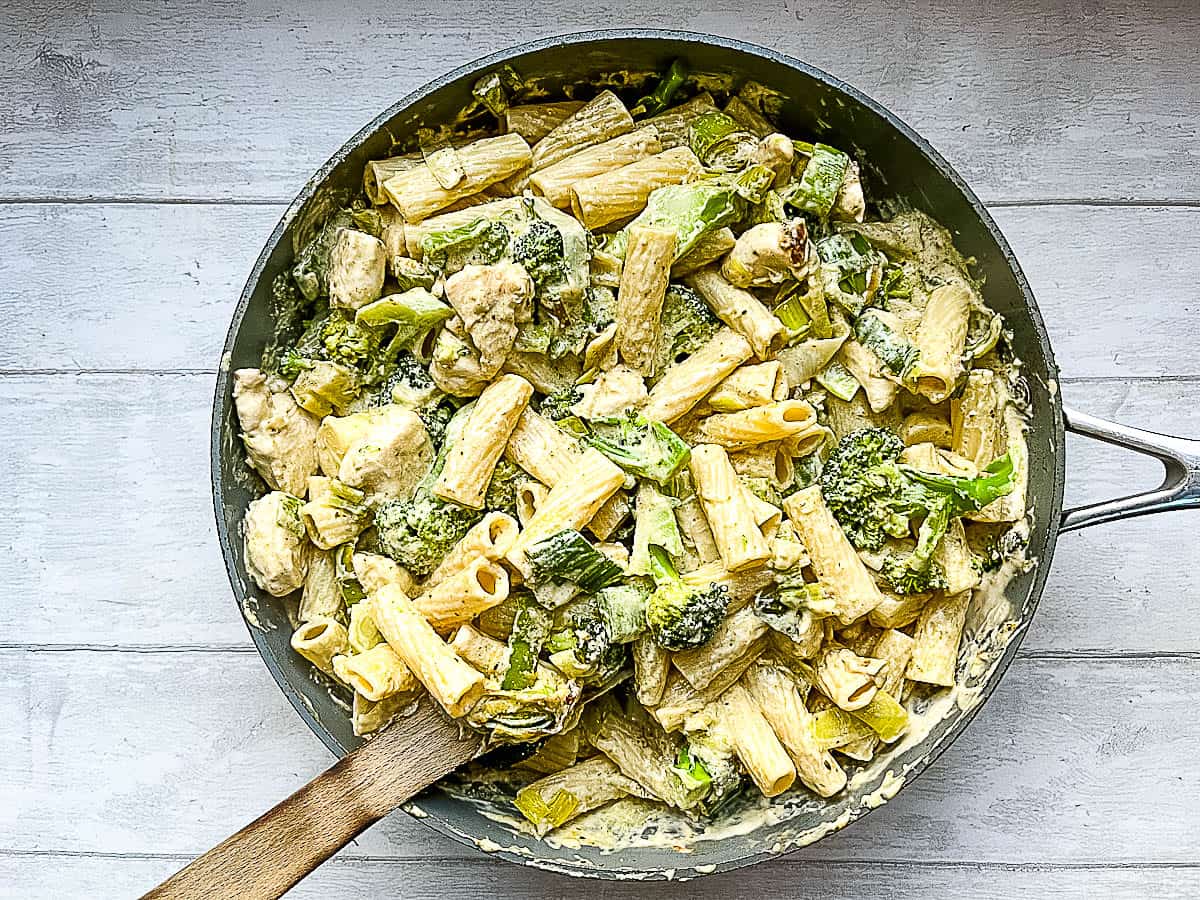 chicken pasta and broccoli added to creamy sauce in pan