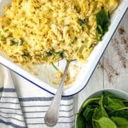 cauliflower pasta bake recipe with portion removed and side of spinach