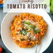 pinterest image for tomato risotto showing finished dish topped with parmesan and fresh basil leaves.