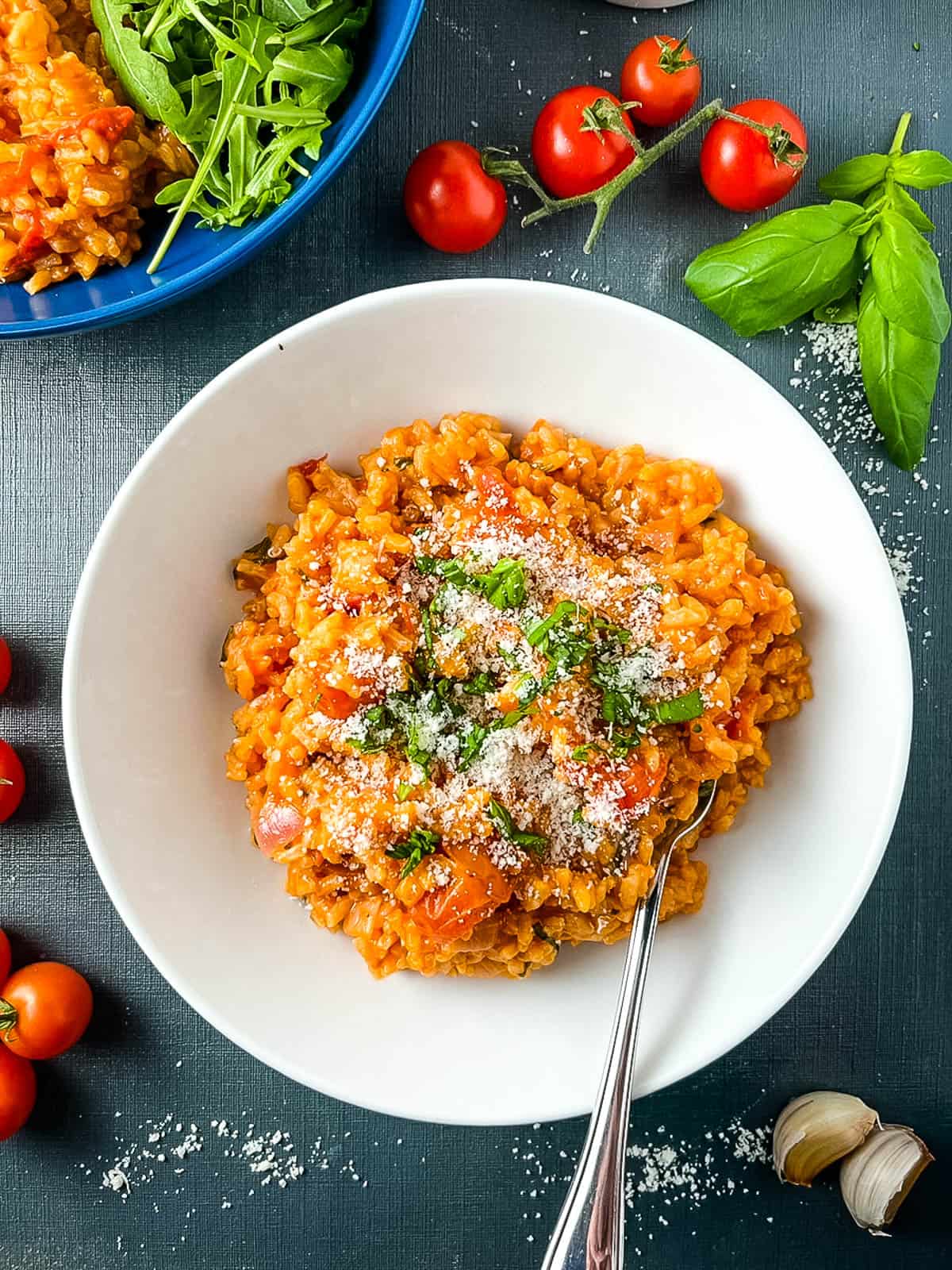 tomato and mascarpone risotto topped with parmesan cheese and fresh basil in bowl