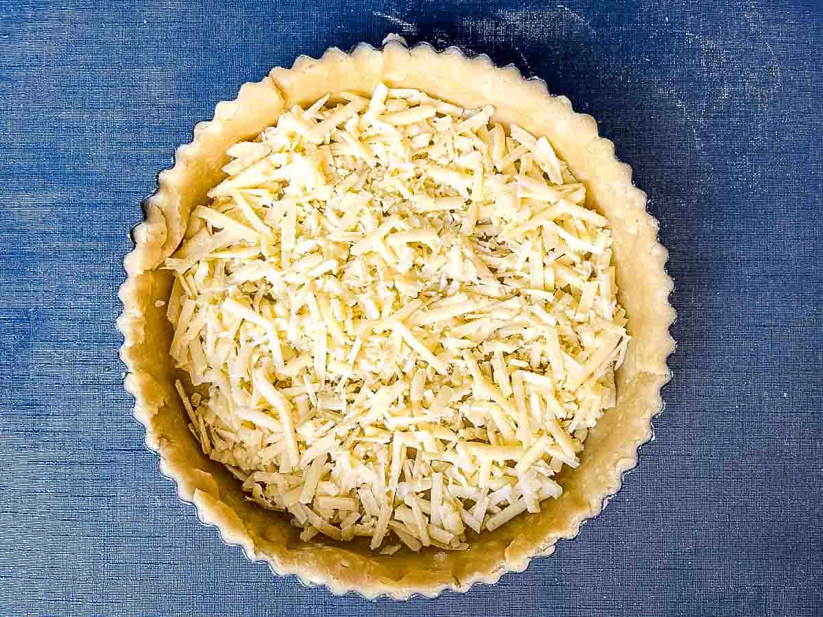 grated cheese spread over pastry base in flan dish