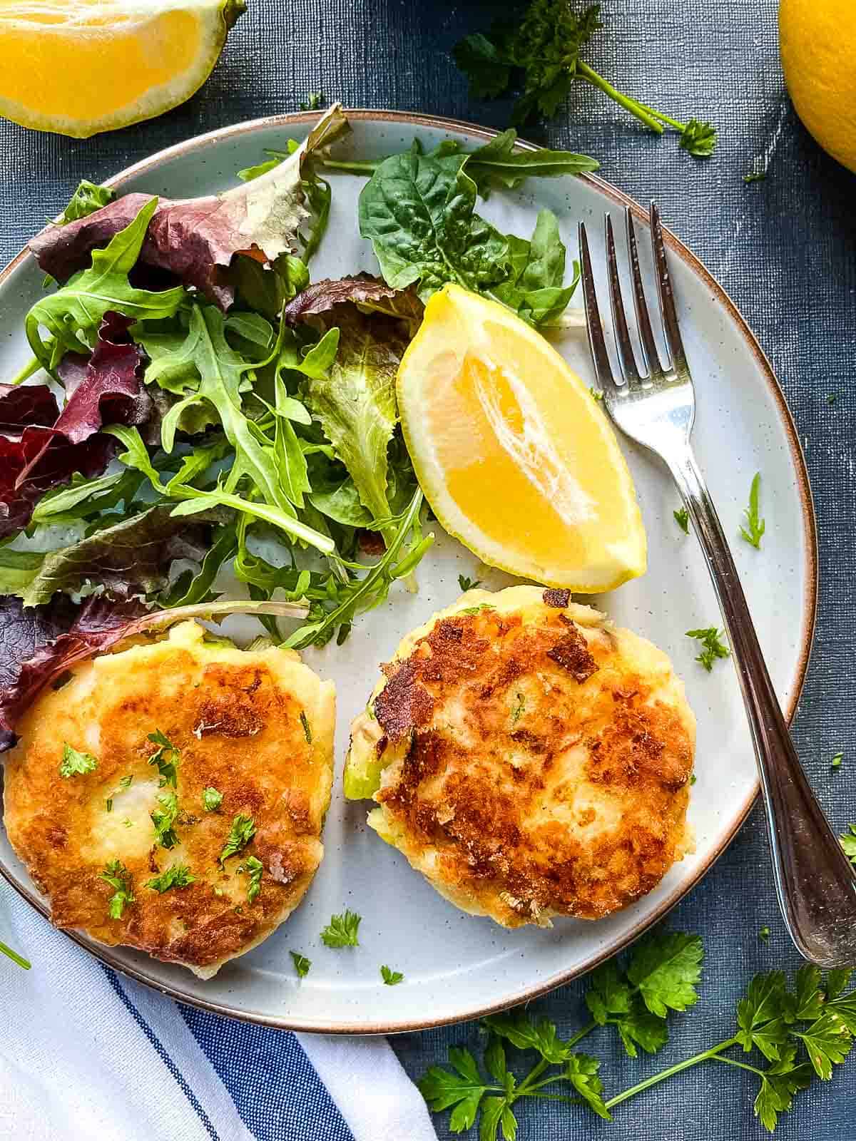 two smoked haddock fishcakes served with salad on a plate