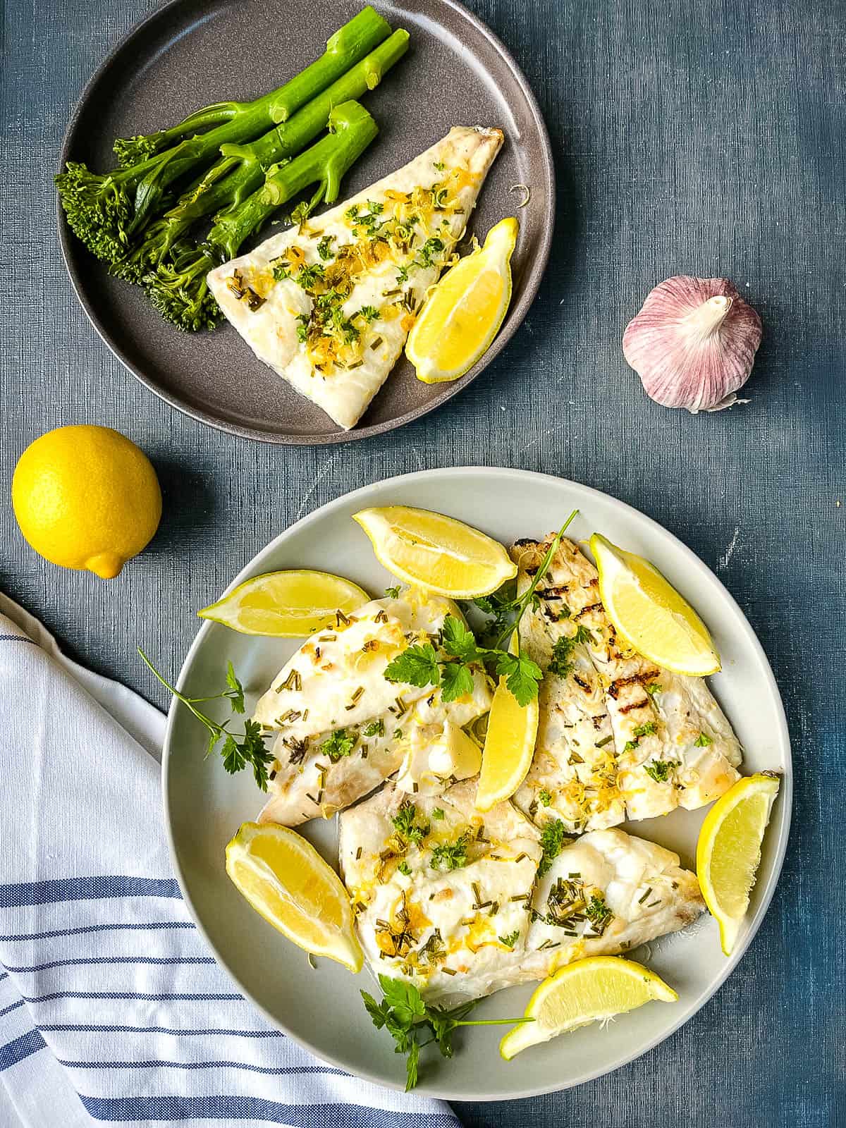 grilled haddock fillets with lemon wedges and dressed with fresh parsley and lemon zest