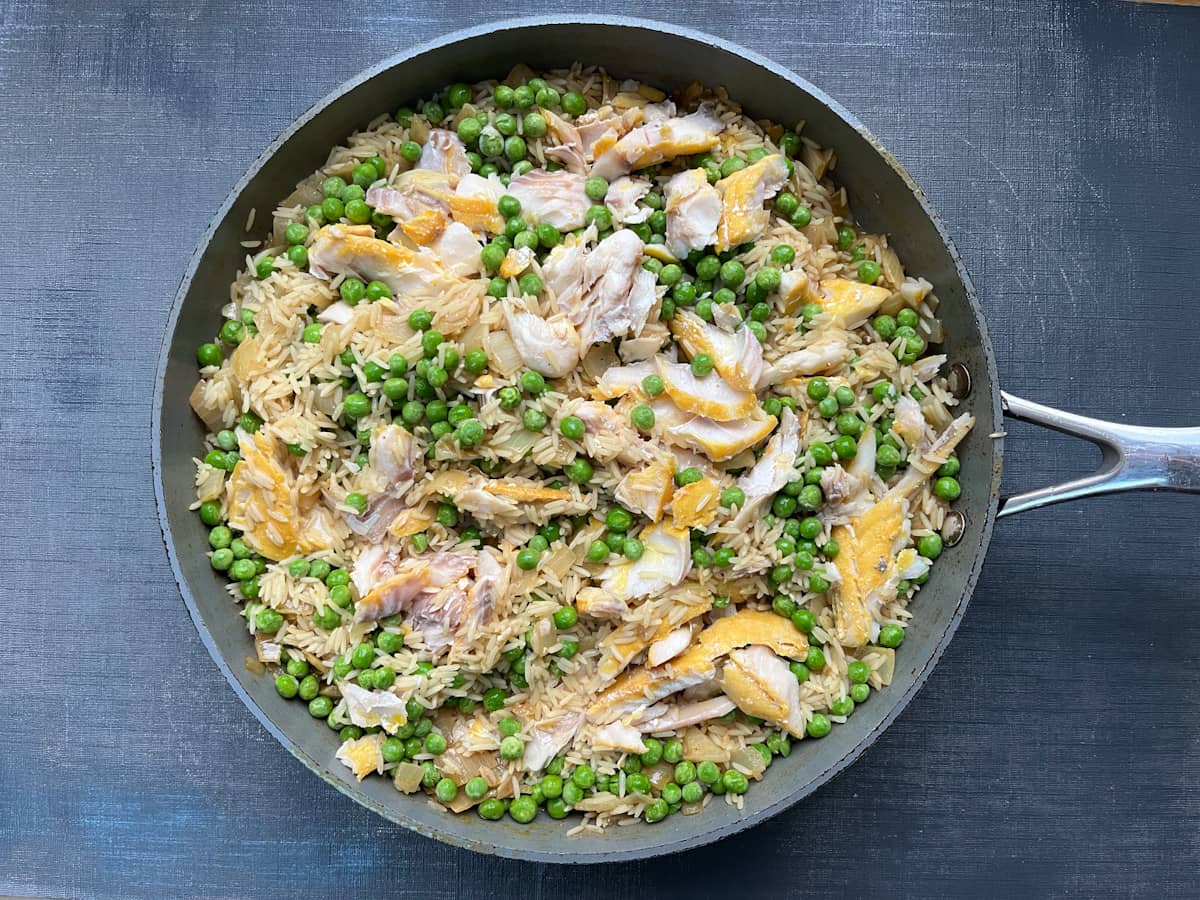 flaked smoked haddock and peas added to curried rice in pan.