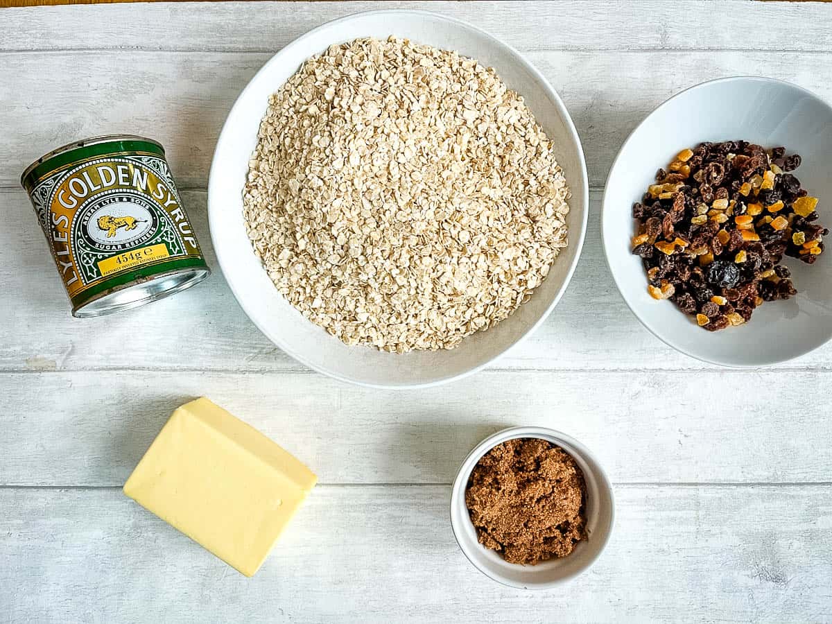 ingredients for fruit flapjacks syrup, rolled oats, dried mixed fruit, butter and dark brown sugar.