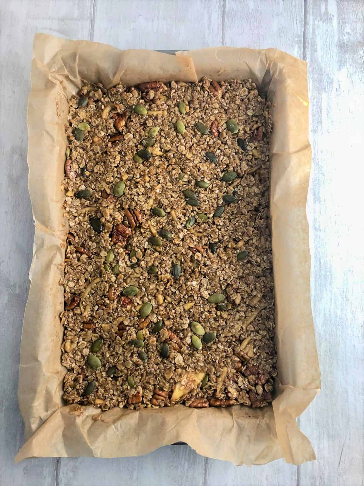mixture for maple syrup flapjacks in baking tray with sunflower seeds on top.