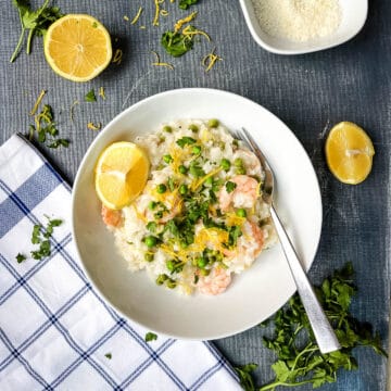 prawn and pea risotto with lemon in bowl topped with fresh parsley and lemon zest