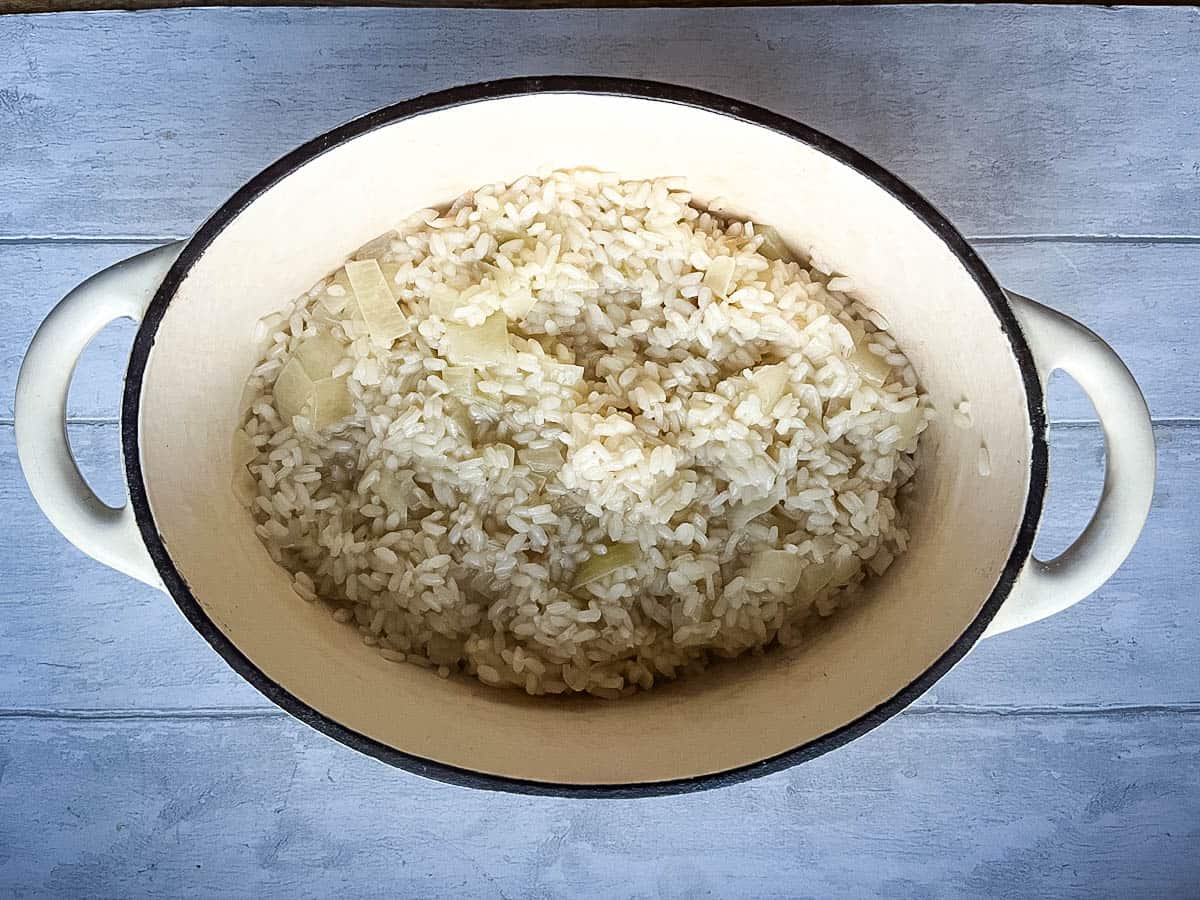 arborio rice simmered in stock in a dish.