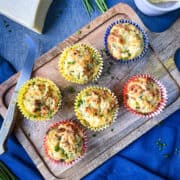 cheese and courgette (zucchini) muffins on a wooden board with fresh chives.