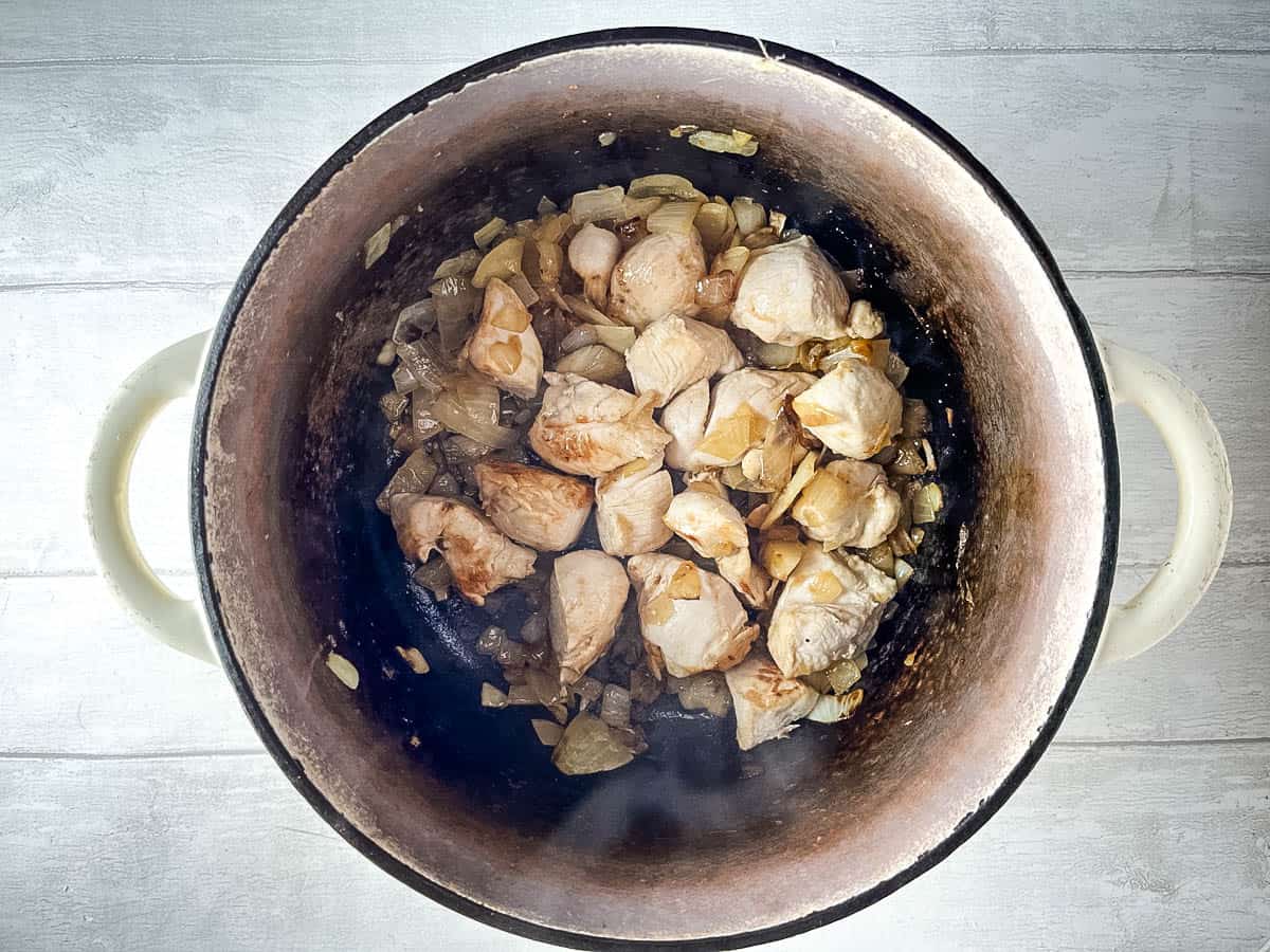 onion and diced chicken frying in pan