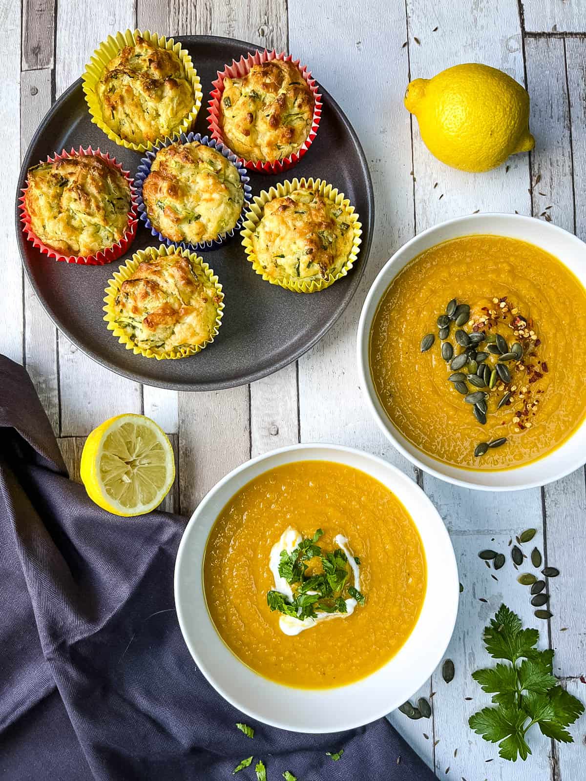 bowls of carrot and cumin soup served with a side of cheese and courgette muffins.