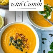 bowls of carrot and cumin soup served with chilli flakes and pumpkin seeds and fresh coriander (cilantro).