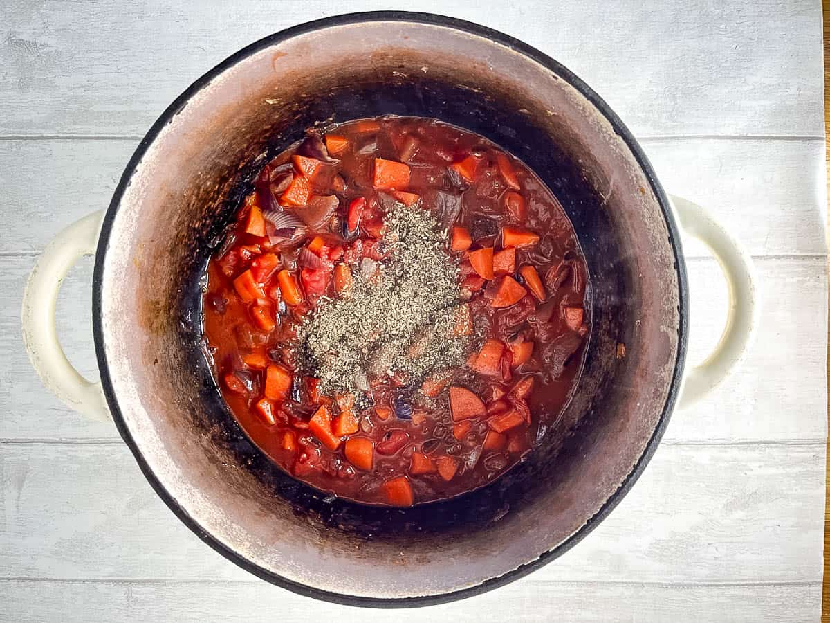 italian seasoning and chopped tomatoes added to red onion and carrot in stove top pan.