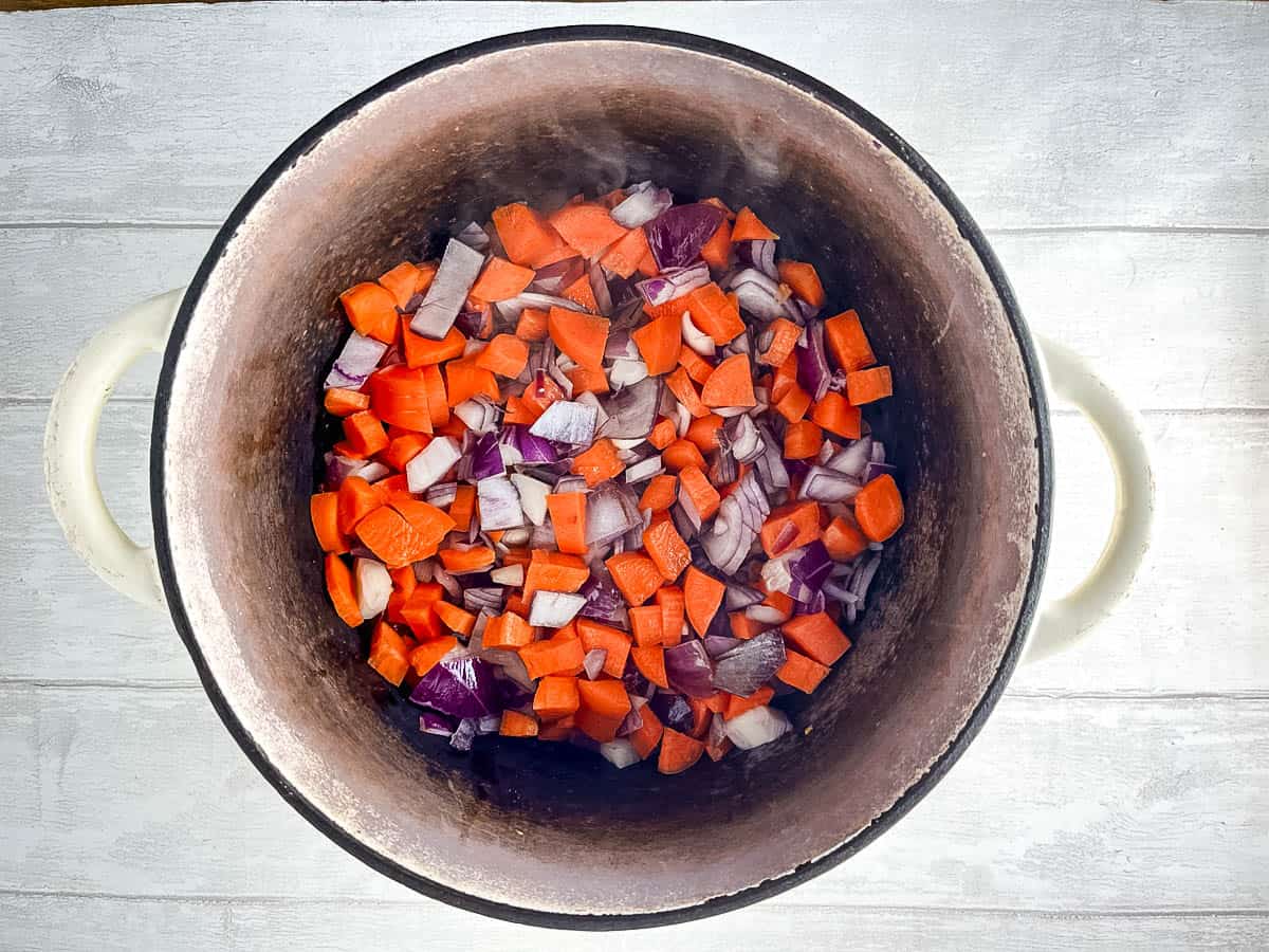 diced onion and carrots frying in stove top pan.