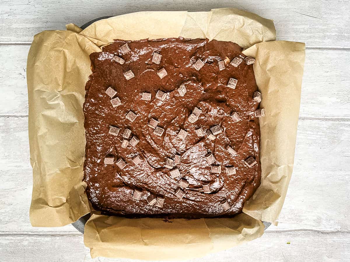 brownie mixture in a tray topped with chocolate chips ready for the oven.