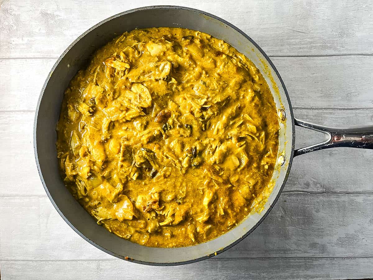 chicken curry in sauce with natural yoghurt in pan.