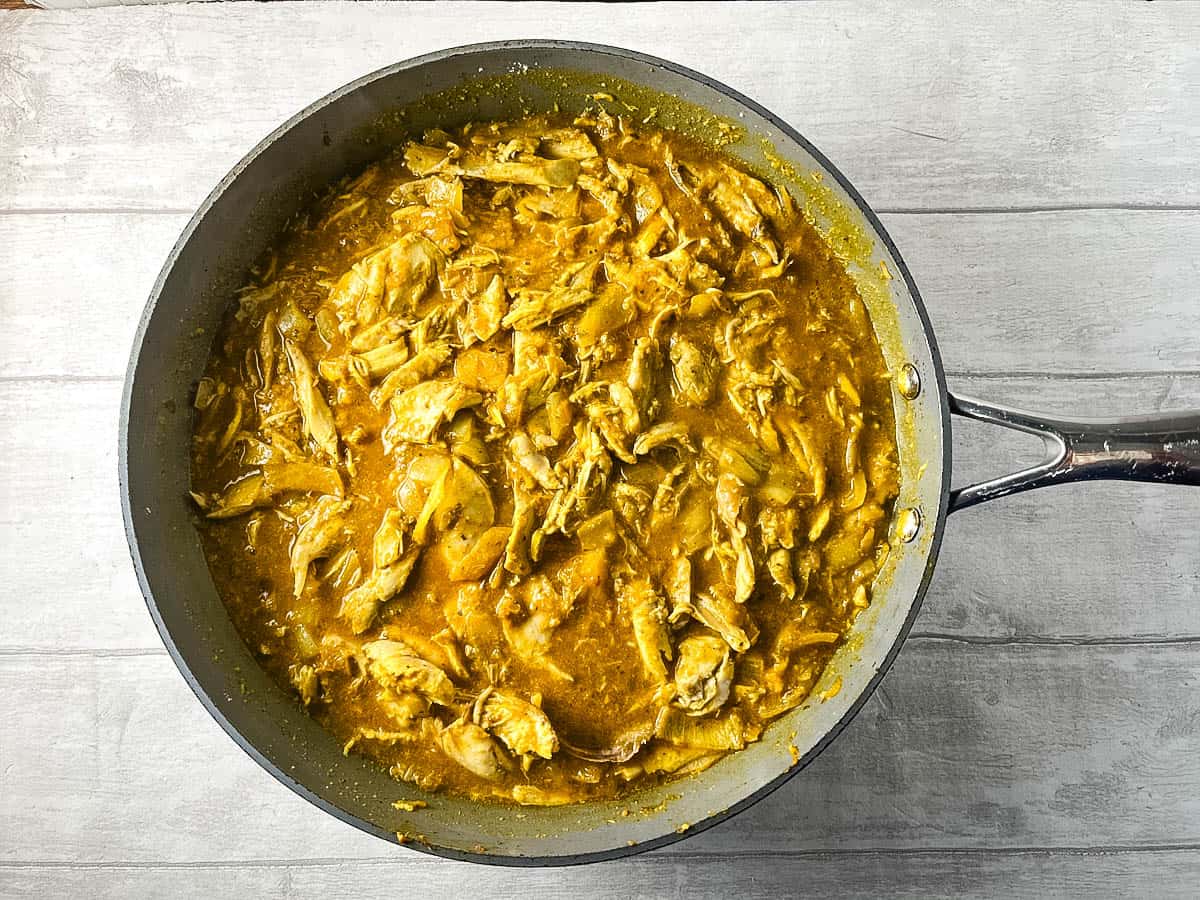 chicken stock added to cooked chicken and curry paste in pan.