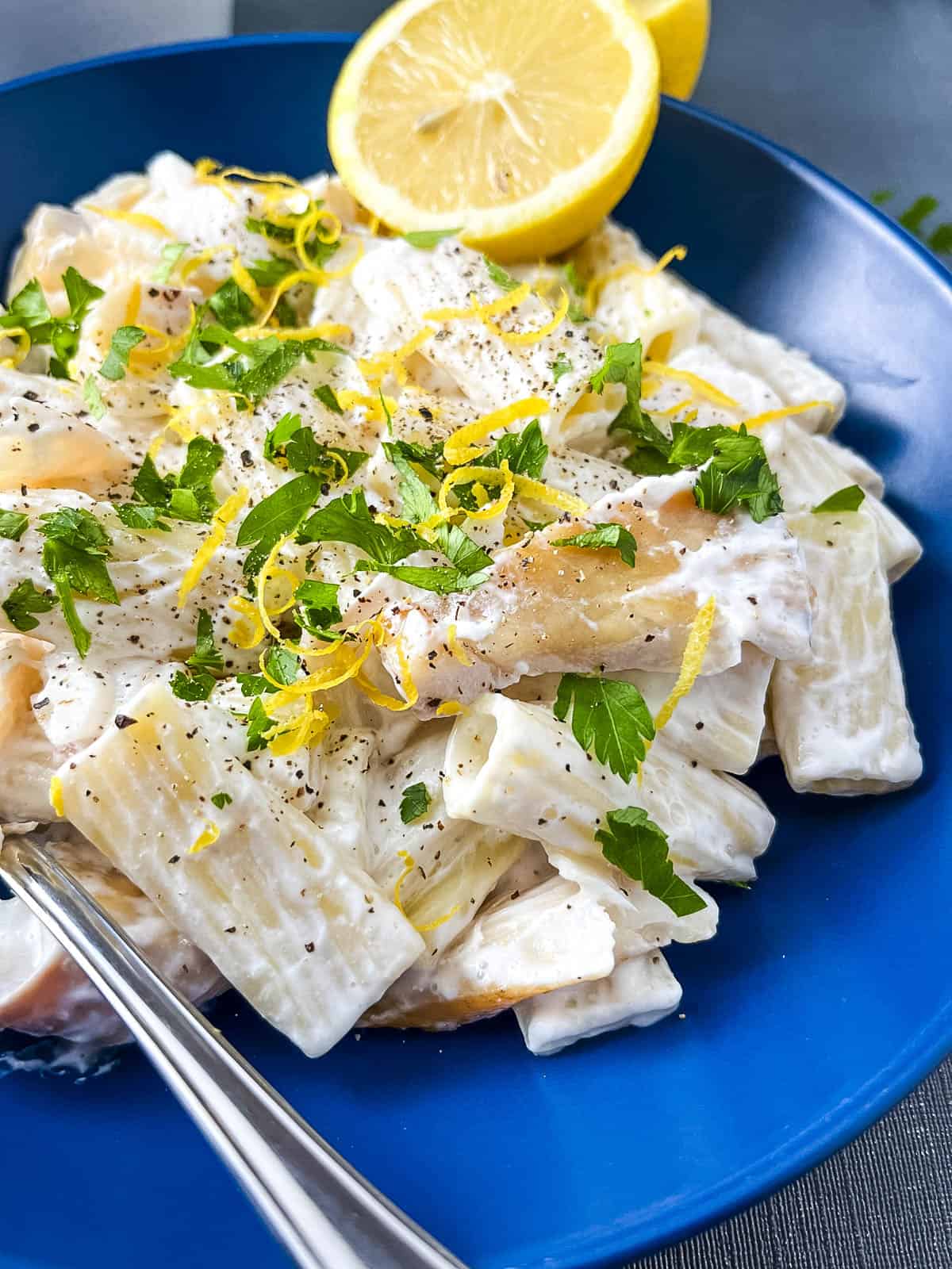 close up of bowl with smoked haddock and pasta in a creamy lemon sauce topped with fresh parsley and lemon zest.