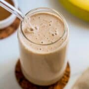 glass of banana almond butter smoothie with straw.