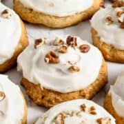 banana cookies with cream cheese frosting topped with pecan nuts