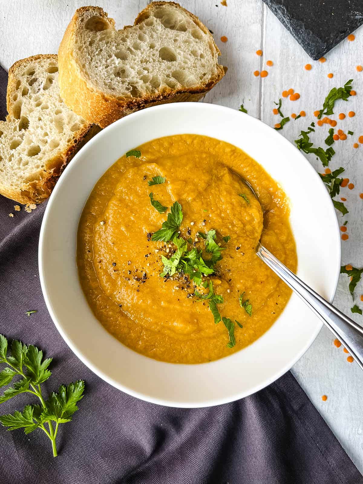 bowl of red lentil and leek soup topped with fresh parsley.