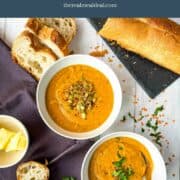 two bowls of red lentil soup served with baguette and topped with fresh parsley and pumpkin seeds.
