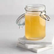 jar of banana syrup on marble coasters.