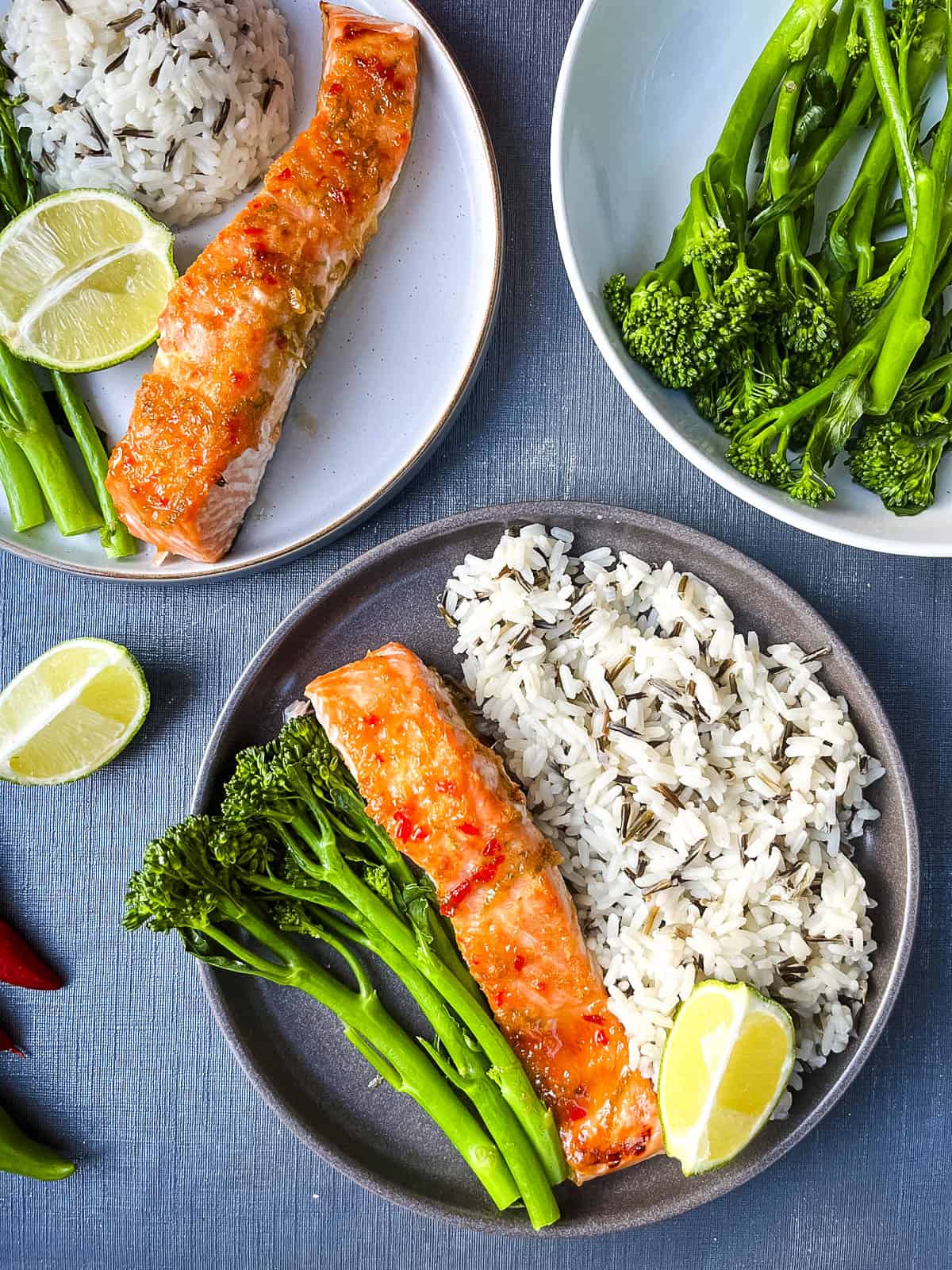 two plates of baked salmon fillet served with wild rice and tender stem broccoli.