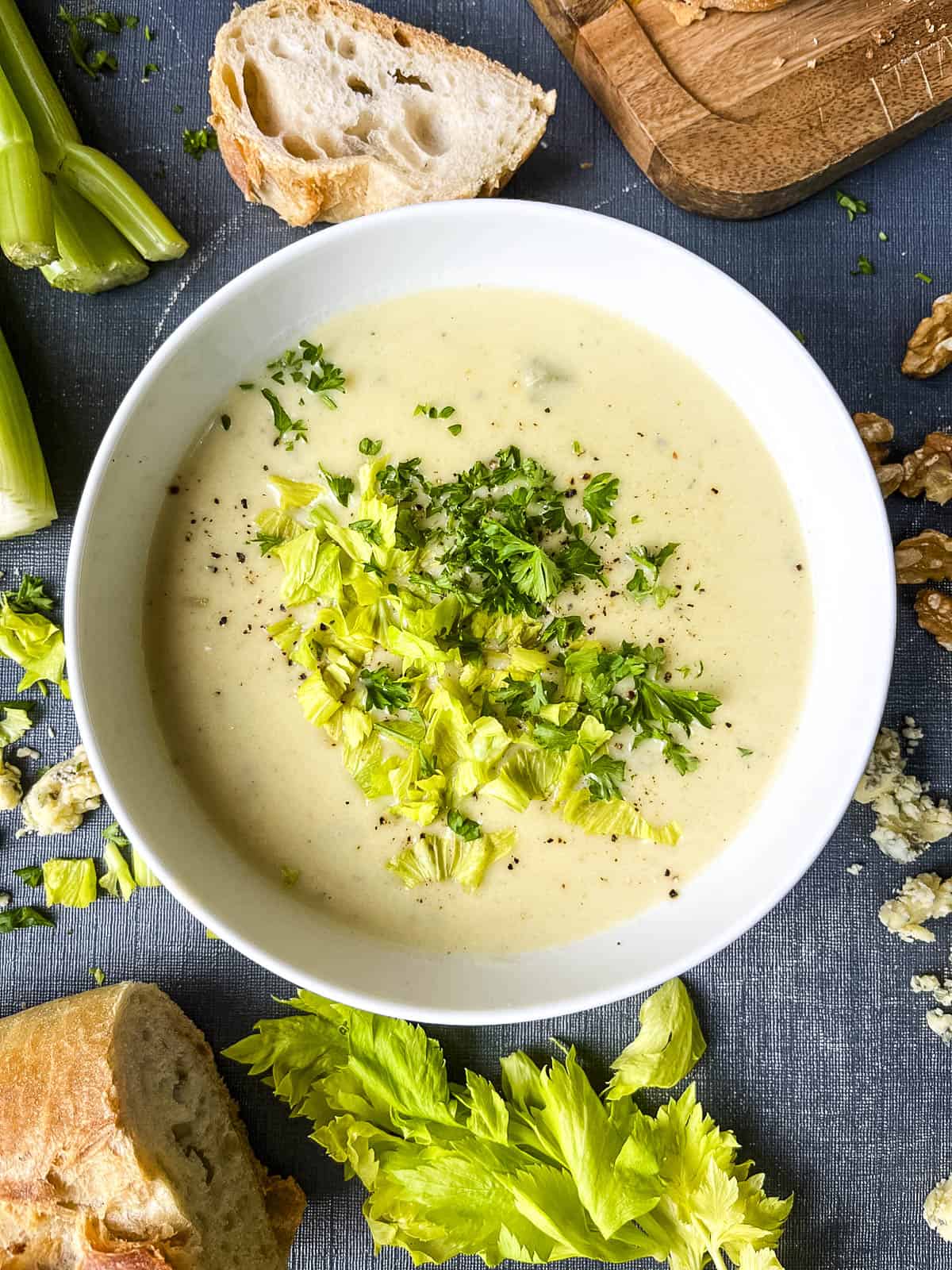 bowl of stilton and celery soup topped with celery leaves and parsley.