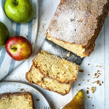 sliced apple and pear loaf on a board dusted with icing sugar