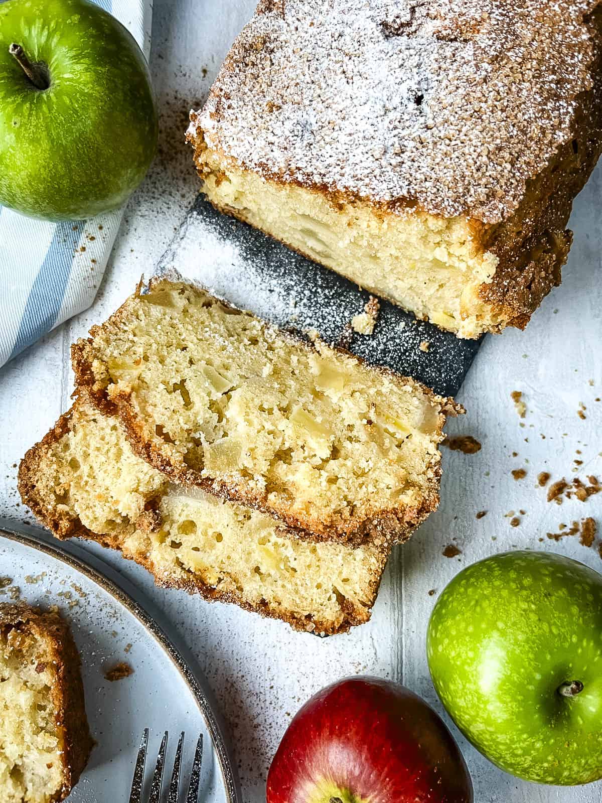 sliced apple and pear cake on a board dusted with icing sugar.