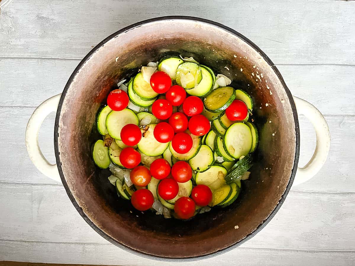 diced courgette cherry tomatoes and onion in pan.