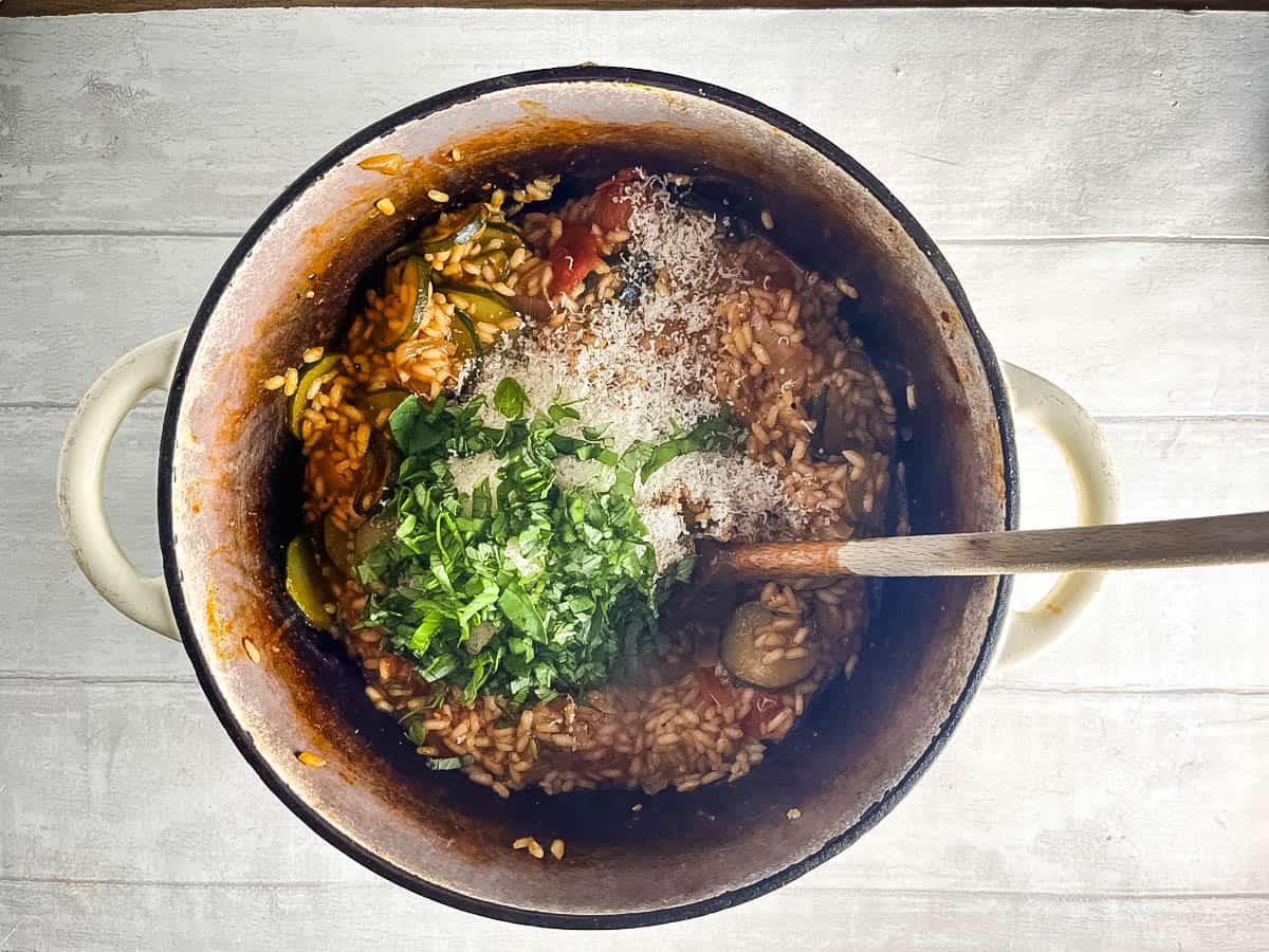 parmesan cheese and basil leaves added to tomato and courgette risotto.