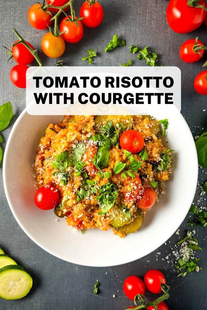 bowl of tomato risotto with courgette topped with fresh basil leaves.