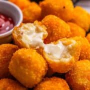 dish of garlic potato cheese balls with one open to show gooey centre.