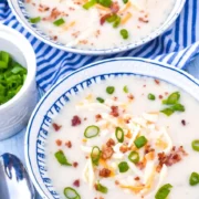 leftover mashed potato soup in bowl topped with spring onions and grated cheese