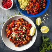 aubergine tagine in a bowl topped with flaked almonds, pomegranate seeds and fresh mint with side of lime.