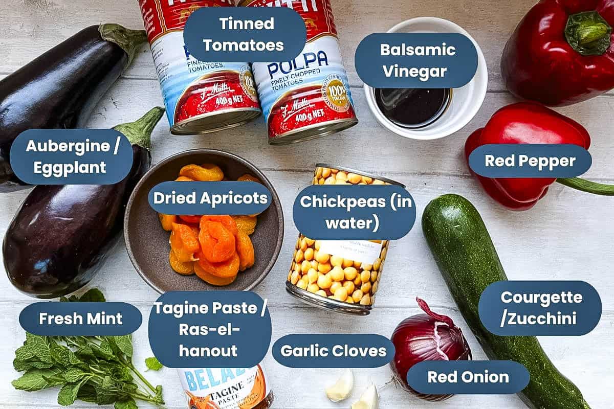 labelled ingredients for Aubergine tagine, aubergine, tinned tomatoes, balsamic vinegar, red pepper, dried apricots, chickpeas, courgette, fresh mint, ras-el-hanout, garlic cloves, red onion.