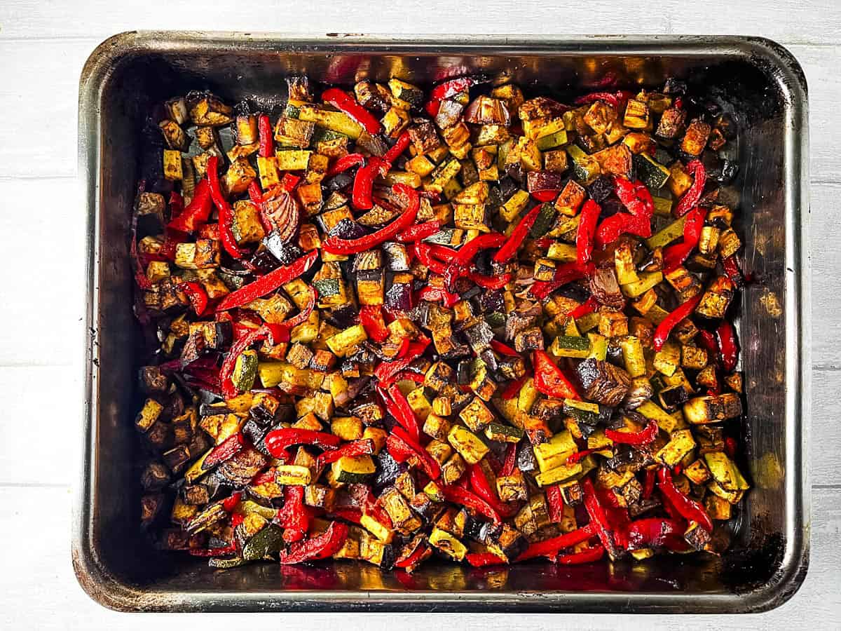 diced aubergine, red pepper, red onion and courgette roasted in tray.