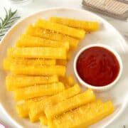 vegan polenta fries on a plate next to a side of tomato ketchup