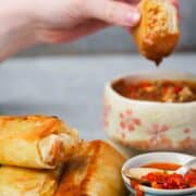 vegan spring rolls being dipped in sauce.