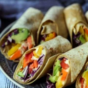 plate of vegan wraps with hummus showing fillings of fresh vegetables