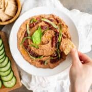black bean hummus in a white bowl with a side of chopped vegetables