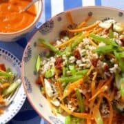 bowl of 3 grain salad with carrot spring onions and mange tout and a side of sauce in a bowl.