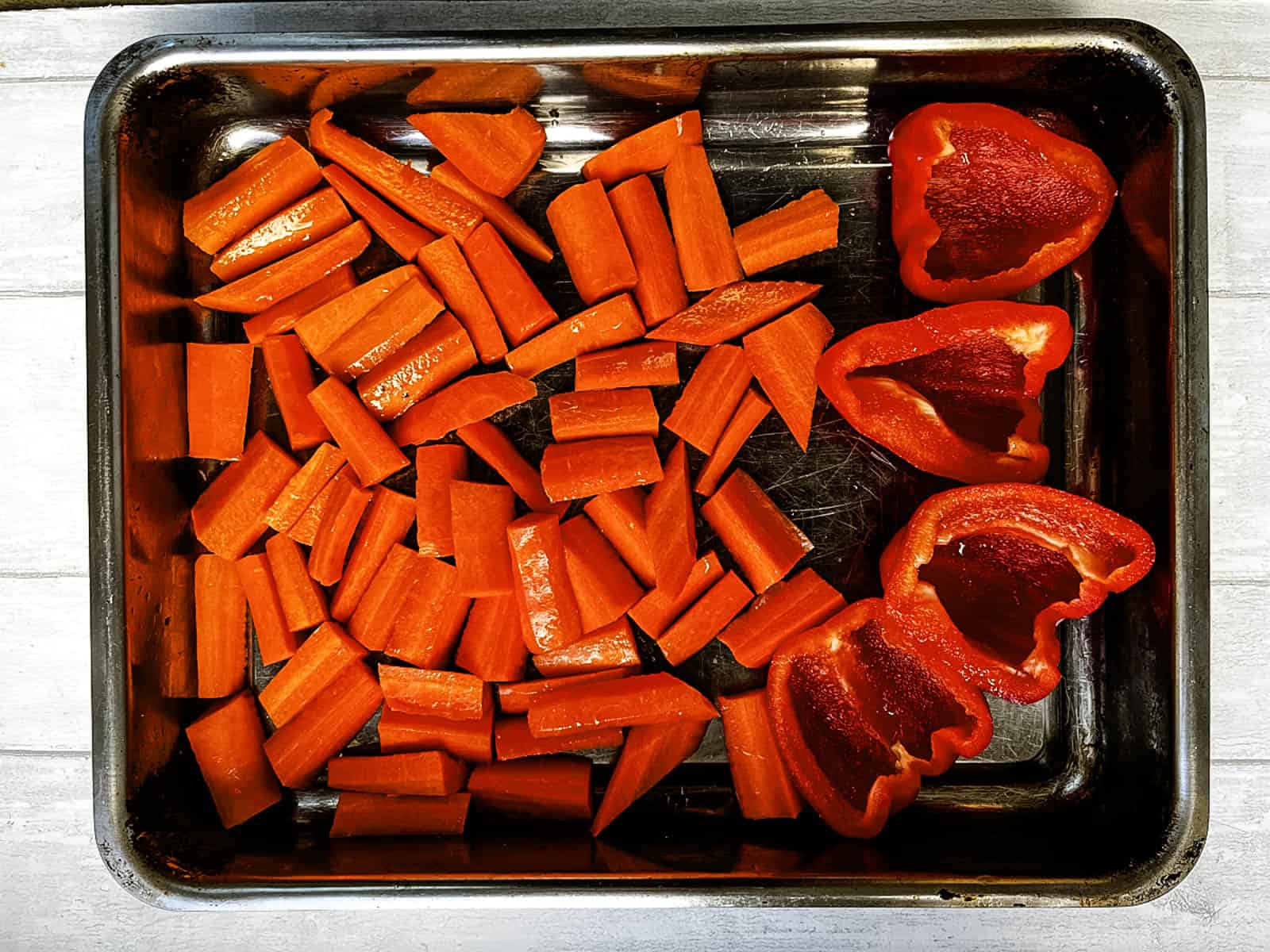 chopped carrots and red bell peppers in a roasting tray