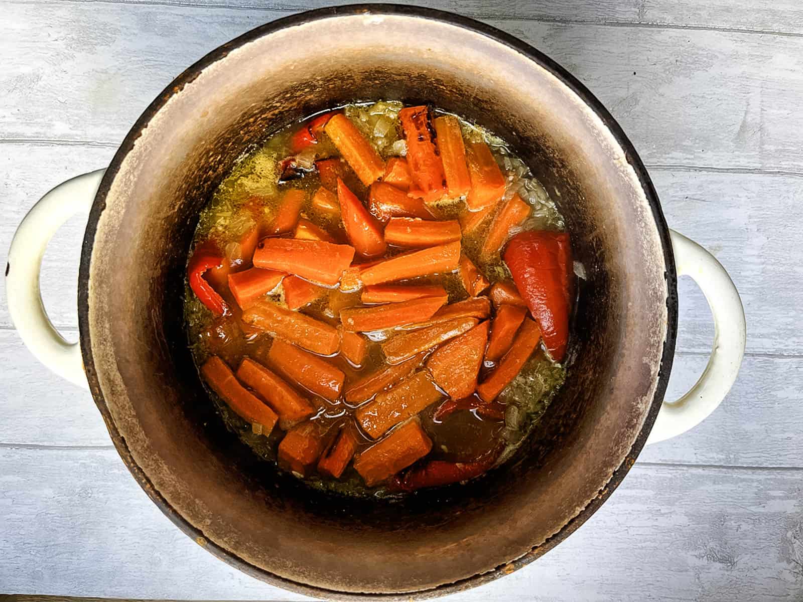 stock added to carrots and red pepper in a crock pot.