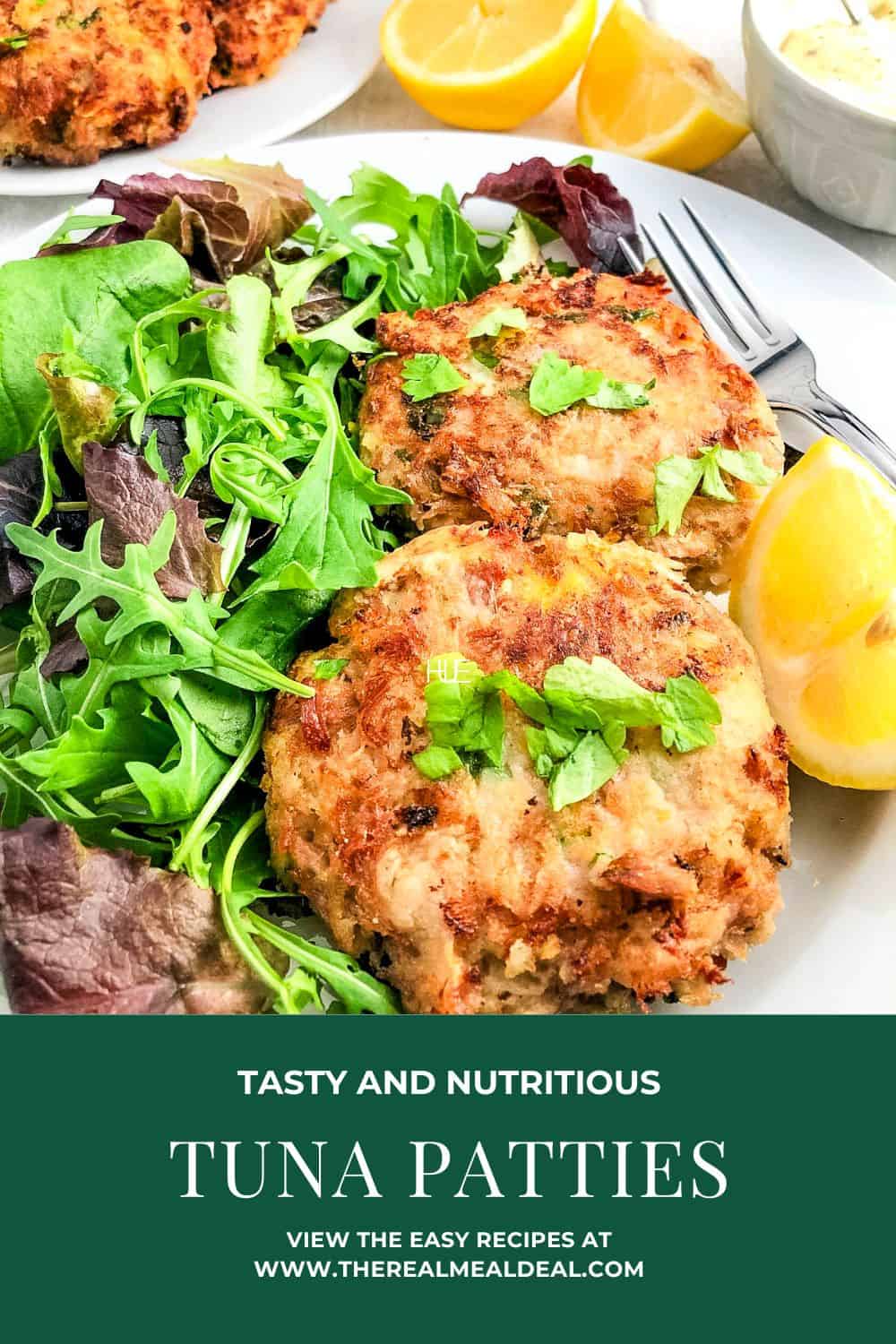 pan fried tuna patties on a plate with a green salad and lemon wedges.
